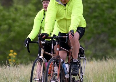 Vivid image of two cyclists in neon jackets riding on a scenic trail, promoting Bluebonnet Express bike tours and outdoor adventure.