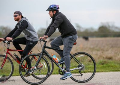 Vibrant biking scene featuring two men riding bicycles through open countryside, promoting outdoor adventure and fitness with Bluebonnet Express.