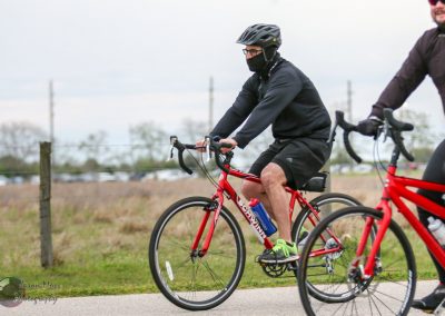 Bright red bicycle in outdoor cycling event with riders dressed in athletic gear and helmets for fitness and recreational biking.
