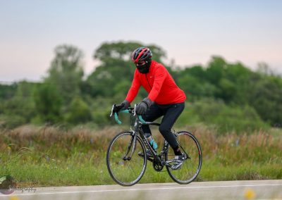 High-performance cyclist on a road bike in a scenic outdoor setting, wearing a helmet and sports gear.