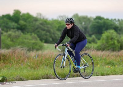 Vegan cyclist riding a road bike through scenic countryside on a cloudy day.