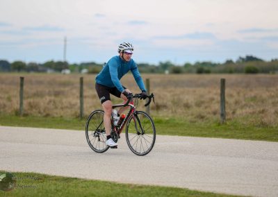 Cyclist riding a road bike on a scenic countryside trail during daytime, enjoying outdoor fitness and cycling adventure.