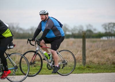 Bright man riding a Cannondale road bike during outdoor cycling event, focused on exercise and biking.
