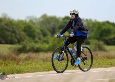 Bike riding woman on scenic trail, Bluebonnet Express cycling tour, outdoor Texas biking adventure.