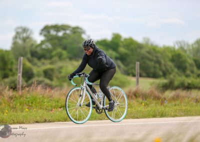 Vibrant woman cycling outdoors on a sunny day, promoting Bluebonnet Express bike rides and eco-friendly transportation.