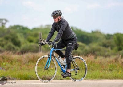 A cyclist riding on a scenic outdoor bike trail, promoting Bluebonnet Express bike services.