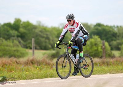 Velo rider on the Bluebonnet Express scenic route amidst lush greenery.