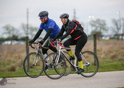 Two cyclists riding bicycles on a paved path during daytime, Bluebonnet Express event.