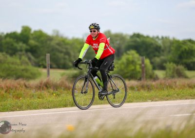Cyclist riding on paved road during daytime, promoting Bluebonnet Express bike event.