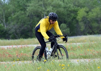 High-performance cyclist riding on scenic trail in Greenfield outdoors, promoting Bluebonnet Express bike service.