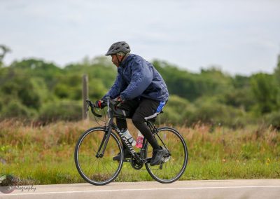 Vegan cyclist riding on a rural road with green landscape, representing Bluebonnet Express cycling tours.