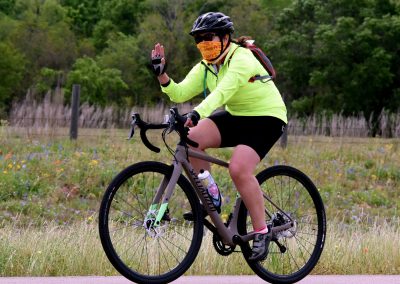 Vibrant cyclist wearing neon yellow jacket and helmet riding a bike through scenic countryside.