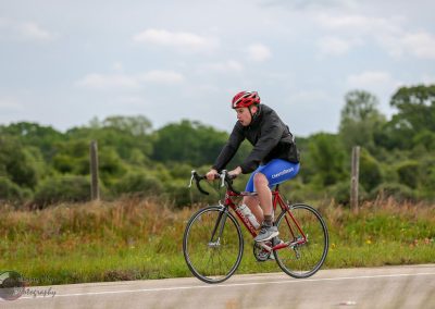Young cyclist riding a red bike with ChevronTexaco logo on a rural road in nature.