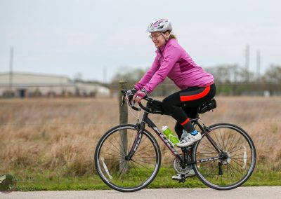 Brightly dressed woman cycling on a scenic Texas trail with Bluebonnet Express branding.