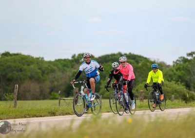 Bicycle group ride on a scenic trail with lush green trees and open sky, promoting outdoor cycling and adventure.