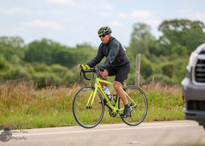 Bright yellow road bike for Bluebonnet Express biking event, rider in black gear on scenic rural route.