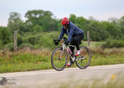 Bright cyclist riding a road bike during daytime on scenic trail in Texas.
