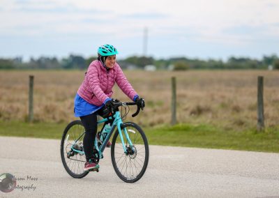 Bright woman cycling outdoors in pink jacket on Bluebonnet Express bike trail.