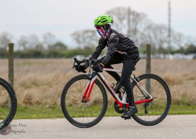 Rider on a red and white Chuech electric bike during a casual outdoor ride on a paved trail.