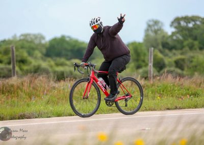 Bright red BMC road bike with water bottle on a scenic countryside road day.