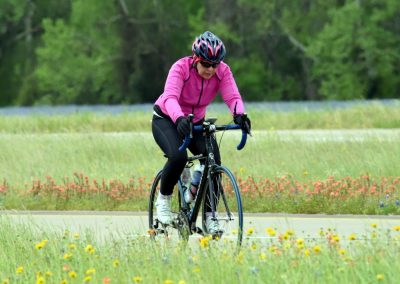 Vibrant cyclist riding through scenic wildflower meadow on Bluebonnet Express trail.