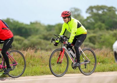 Bright neon yellow cycling jacket on male cyclist riding on scenic outdoor trail during daytime.