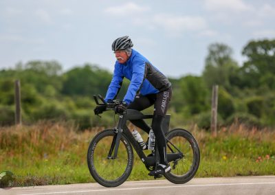 Vivid image of an elderly man cycling on a scenic countryside road, highlighting fitness and outdoor adventure.
