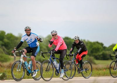 Bright blue and pink cycling jerseys, smiling cyclists on scenic outdoor bike ride.