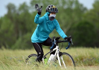 Cyclist wearing helmet and mask riding a bike on a trail.