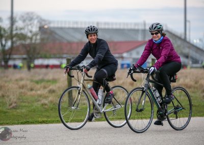 Vibrant women cycling outdoors with Bluebonnet Express bikes in scenic park setting.