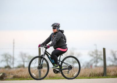 Vibrant woman cycling on a Black Bluebonnet Express mountain bike on a cloudy day.