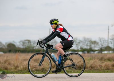 Bright yellow helmet, mountain bike rider on a scenic outdoor trail, promoting Bluebonnet Express cycling tour.