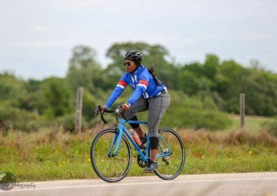 Vibrant cyclist riding Bluebonnet Express bike on scenic rural road outdoors.