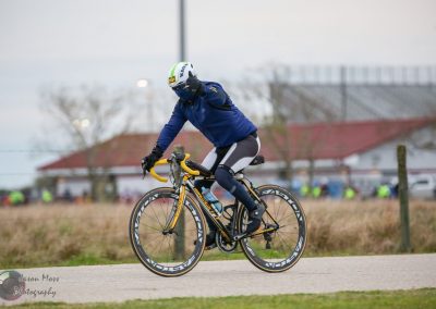High-performance cyclist riding a yellow and black road bike outdoors during daytime.