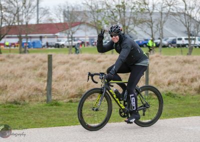 Cyclist in black gear riding a high-performance bike outdoors, promoting Bluebonnet Express cycling event.