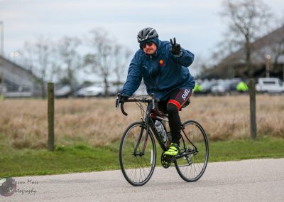 Cyclist wearing safety gear riding a road bike in outdoor event, promoting safety and active lifestyle.