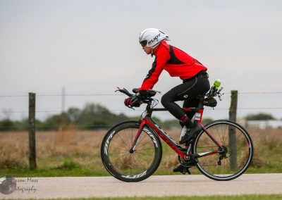 Velo cyclist riding on scenic rural road, emphasizing endurance and outdoor adventure.