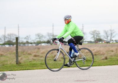 Bright green cycling jacket, riding a bicycle outdoors during daytime.