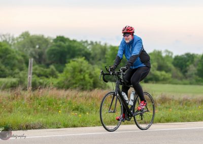 Vibrant cyclist riding a black e-bike along a scenic rural trail in spring nature.