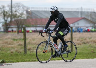 High-performance cyclist wearing protective gear riding a carbon fiber bike outdoors in a park setting.