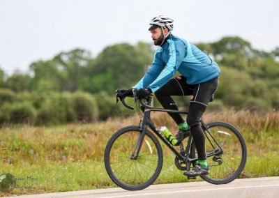 Bright blue cyclist jersey on a mountain bike riding on a scenic trail with lush greenery background.