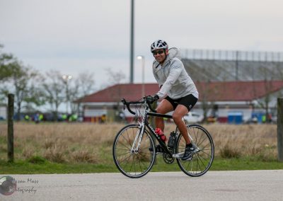 Active man riding a black road bike during daytime outdoors.