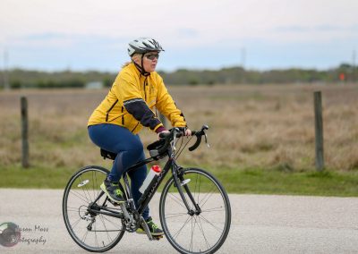 Bright yellow jacket-wearing cyclist riding a bike outdoors on a scenic open trail.