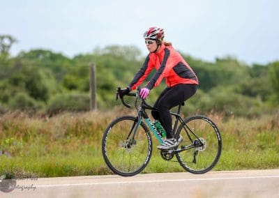 Vibrant cyclist on a Canyon road bike riding through scenic green countryside.