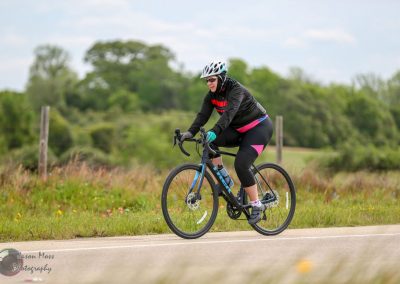 A woman riding a blue biking trail through scenic countryside on a sunny day.