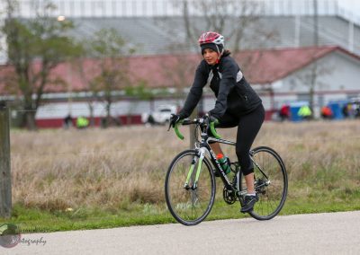 Bright green and black road bicycle with woman cyclist on a scenic outdoor trail.
