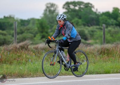 Vibrant female cyclist riding a road bike outdoors in nature, promoting eco-friendly transportation and outdoor adventure.