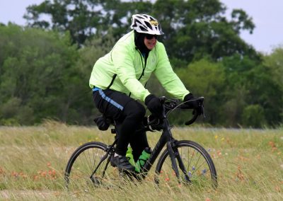 Vibrant cyclist wearing a bright yellow jacket on a mountain bike in a grassy field with wildflowers.