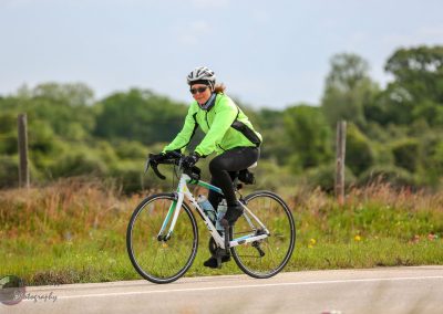 Bright green cycling jacket on woman riding bike on scenic rural trail.