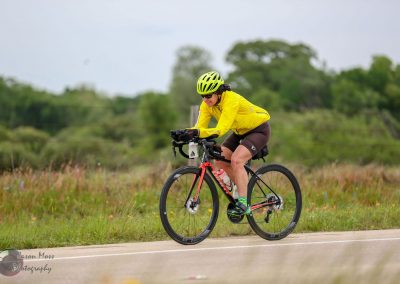 High-performance cyclist riding on a scenic open-road route for Bluebonnet Express event.